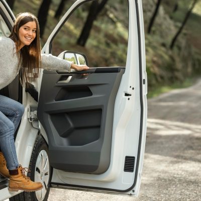 vista-lateral-mujer-sonriente-saliendo-coche-viaje-carretera_23-2148851244